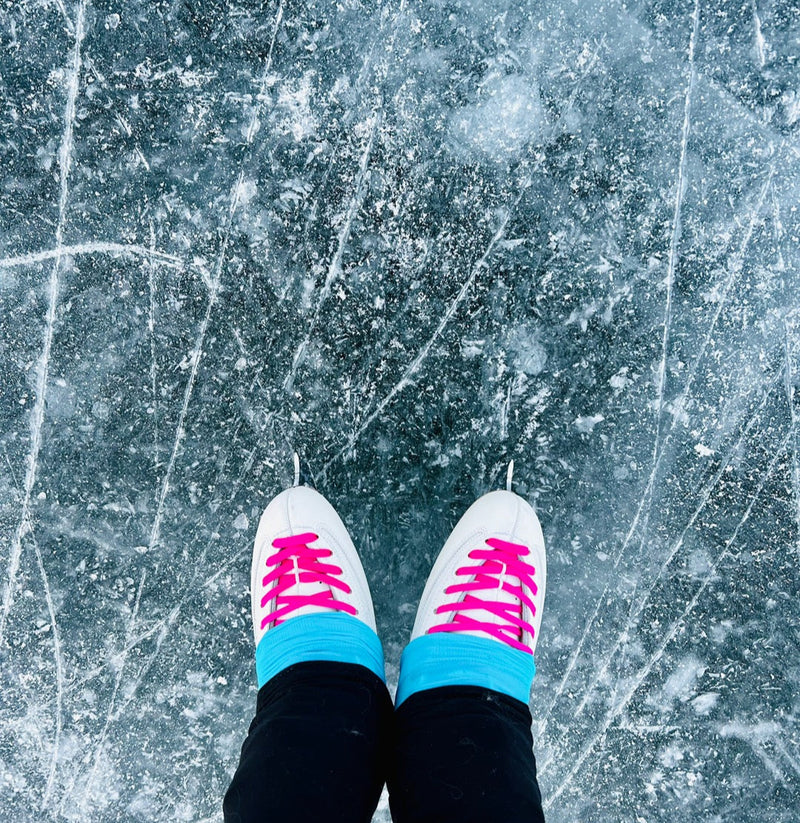 Figure skates with pink laces on the ice, seen from above